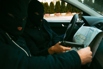 Bank robbers with their masks on pointing at the map prepared for robbing the bank,sitting in the...