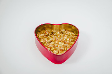 Top view of a heart shaped box with pills inside isolated, white background. Medical concept, care for the heart, eating pills strengthening the heart. Prevention of heart attack, hypertension.