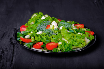 Fresh salad with various vegetables on dark background.
