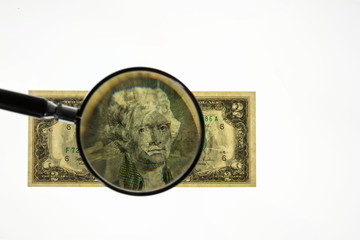Close up view of magnifying glass over two dollar bill. Banknote. Beautiful backgrounds. 