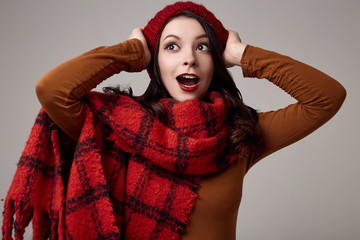 Beautiful brunette woman in sweater and red hat with big knitted scarf