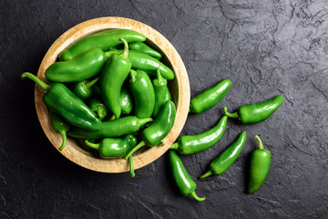 Green jalapeno hot pepper in wooden plate closeup. Food photography - obrazy, fototapety, plakaty