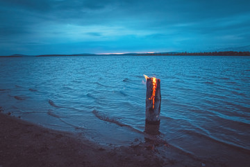 Burning log on the shallows of the lake