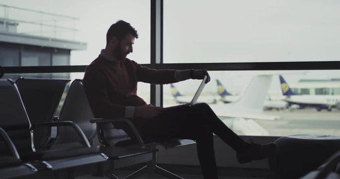 In the airport in a waiting aria businessman working on his notebook till waiting for the flight, then he finished the work and go to the boarding