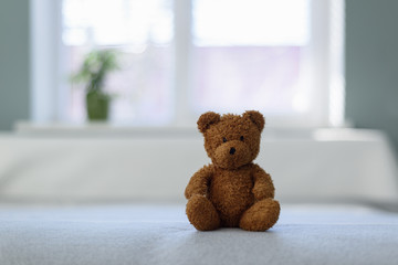 Plush teddy bear toy on white bed. Childhood concept