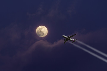A plane flying towards a beautiful moonlight