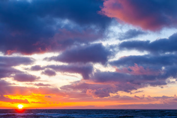picturesque seascape with colorful clouds and bright sunshine during sunset