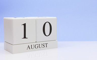 August 10st. Day 10 of month, daily calendar on white table with reflection, with light blue background. Summer time, empty space for text
