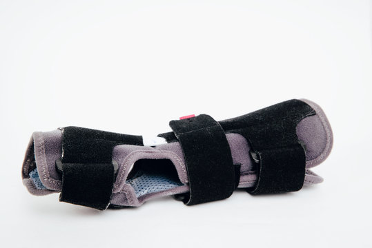 Gray-black orthosis on white, isolated background. Protective wrist brace stiffens the hand, joints during injury. Replacement of gypsum and splint with orthosis. Help with hand injuries. Hand pain.
