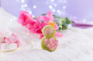 Decorative figure eight with beautiful bouquet of tender pink tulips and marshmallow on blurred lilac background with bokeh.