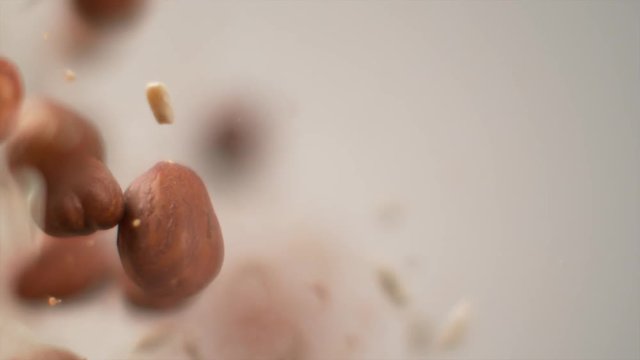 SLOW MOTION, DOF, MACRO: Cool detailed shot of hazelnuts and small brown particles exploding into the camera. Tasty pine nuts and delicious dried hazelnuts blast at the camera. Blurry nut blast.