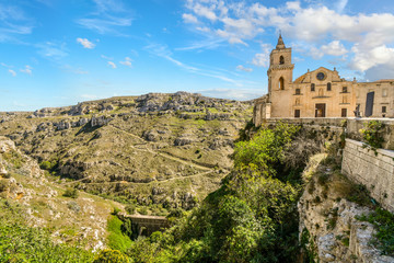Fototapeta na wymiar The Church of San Pietro Caveoso sits atop a steep cliff and overlooks the canyon, ravine and prehistoric sassi cave dwellings in Matera, Italy.
