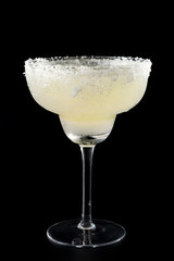 Exotic cocktails and mexican culture concept theme with a glass of margarita cocktail with salt on the brim isolated on dark black background