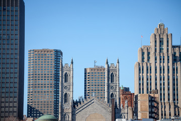Skyline of the Old Montreal, with the Notre Dame Basilica in front, and a vintage stone Skyscraper in the background. The basilica is the main cathedral of Montreal, Quebec, Canada