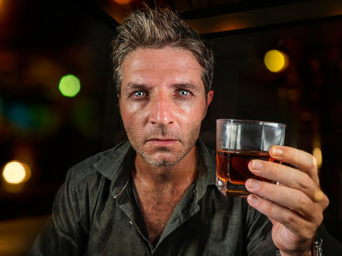 messy and wasted man drunk at night club or bar drinking whiskey glass looking hammered celebrating party or suffering alcoholism problem and alcohol addiction