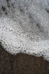 Abstract water bubbles on a black and brown sand beach