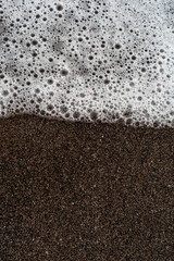 Abstract water bubbles on a black and brown sand beach