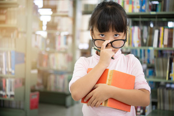 Cute asian little girl with holding glasses reading a books