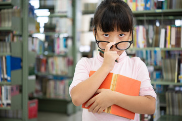 Cute asian little girl with holding glasses reading a books