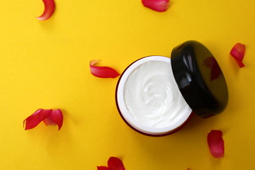 Red bottle with cosmetic cream on yellow background