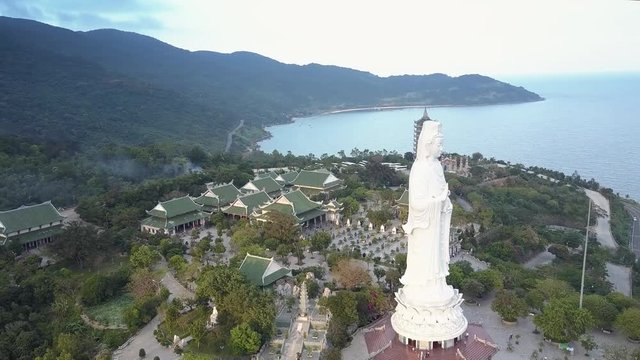 wonderful aerial view huge buddha statue on hilltop near ocean against pagoda and buildings with triangular roofs
