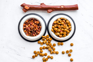 Animal food in bowl on white stone background top view