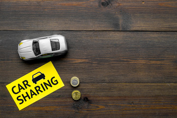 Carsharing concept, carsharing sign. Economical, chip trip. Toy car near coins on dark wooden...