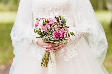 delicate stylish bouquet of roses in the hands of the bride outdoors