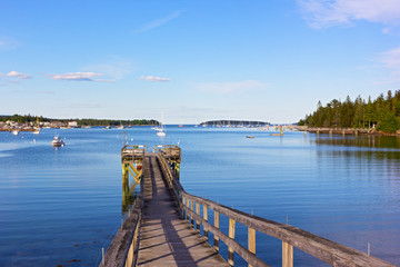 Fototapeta premium A wooden pier at Bar Harbor, Maine, USA. Scenic panorama with yachts and motorboats on quiet waters of the harbor.