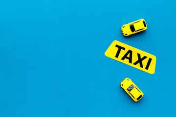 Taxi concept. Yellow service sign text taxi near car toy on blue background top view space for text