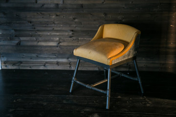 Metal stool with soft upholstery in loft style against a wooden wall. Free space for text.