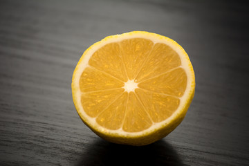 Freshly cut yellow lemon in half against a black table