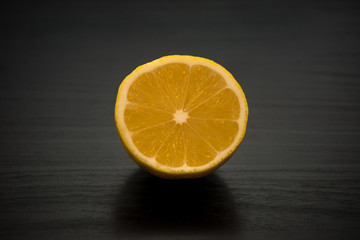 Freshly cut yellow lemon in half against a black table