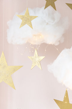 Christmas background. Christmas card. Clouds made of cotton with light, hanging by a thread. Star gold color. Cozy photo zone for a photo shoot. Children's room decoration.