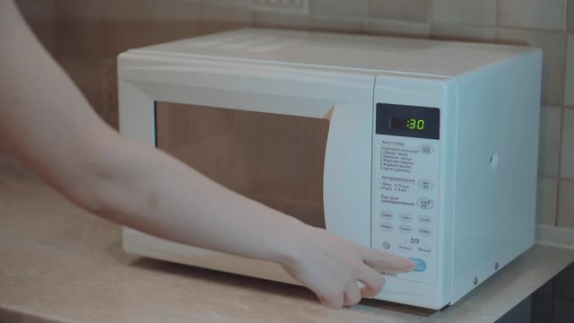 Heated food in the microwave. Female hand puts pies in the microwave in the lunch box. Cooking in the microwave. 4k video.