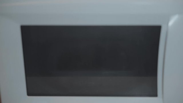 Heated food in the microwave. Female hand puts pies in the microwave in the lunch box. Cooking in the microwave. 4k video.