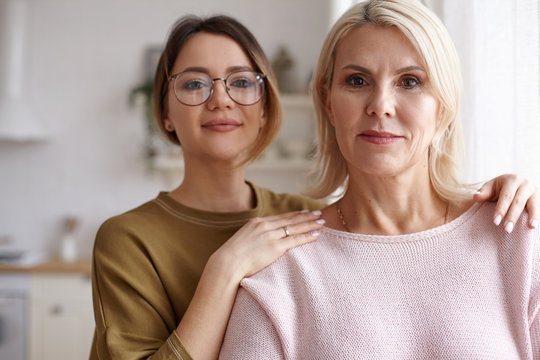 Family, love, relationships, affection, generation, youth and aging concept. Close up shot of beautiful blonde mature woman in her forties spending day with her adorable young daughter wearing glasses