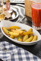 Baked unpeeled potatoes on white plate with tomato juice on the table