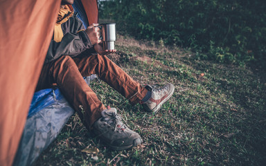 hiker man in the tourists tent and holding a coffee cup on the mountain. travel concept.