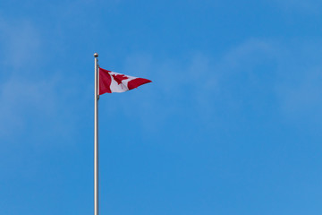 Canadian flag against bright blue sky, with copy space