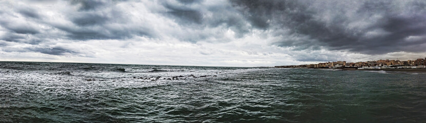 Seascape of winter sea with dramatic sky and dangerous weather, sea's waves crash on the shore