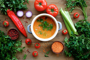 Lentil soup in pan with ingredients on wooden table. Healthy lifestyle concept