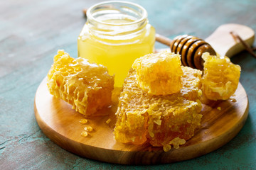 Fototapeta na wymiar Natural Honey. Honey in glass jar and dipper, Sweet Honeycombs on blue stone table.