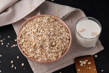 Oatmeal in a plate and a cup of milk on a towel on black background. Healthy food. close up