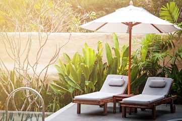 Relax concept. Cozy and comfortable sun beds and beach umbrellas near the swimming pool. Summer vacations still life.