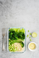 Container with green vegetables and quinoa. Vegetarian lunch with pepper, celery, spinach, broccoli, edamame beans, avocado