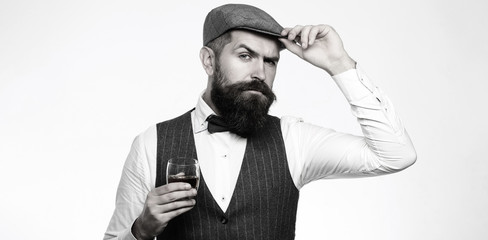 Degustation, tasting. Man with beard holds glass of brandy. Tasting, degustation concept. Bearded businessman in elegant suit with glass of whiskey. Sommelier tastes expensive drink. Black and white.