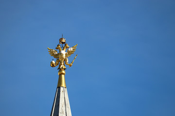 Fototapeta na wymiar Two headed eagle isolated on blue sky background, russian emblem. Snow covered golden coat of arms of Russia on the top of tower on Red square in Moscow, winter weather