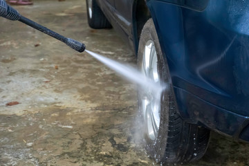 water jet spraying onto the wheel of a car at the car wash center