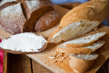 Sliced baguette and round rye black bread. Sandwich with bread, butter and dill. White loaf and rye bread close up and copy space
